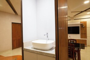 Une salle de bain moderne avec un grand lavabo sur pied, une porte en bois et un coin repas comprenant une table et des chaises.