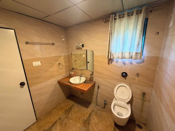 Une salle de bain avec un meuble-lavabo en bois, un miroir, des toilettes et une fenêtre avec un rideau.