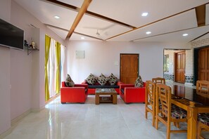 A modern living room with a sofa set, a coffee table, and a dining area with chairs and a table. - Spacious 8-bedroom hotel in welcoming Kashid with AC comfort. (Kashid, Alibaug)