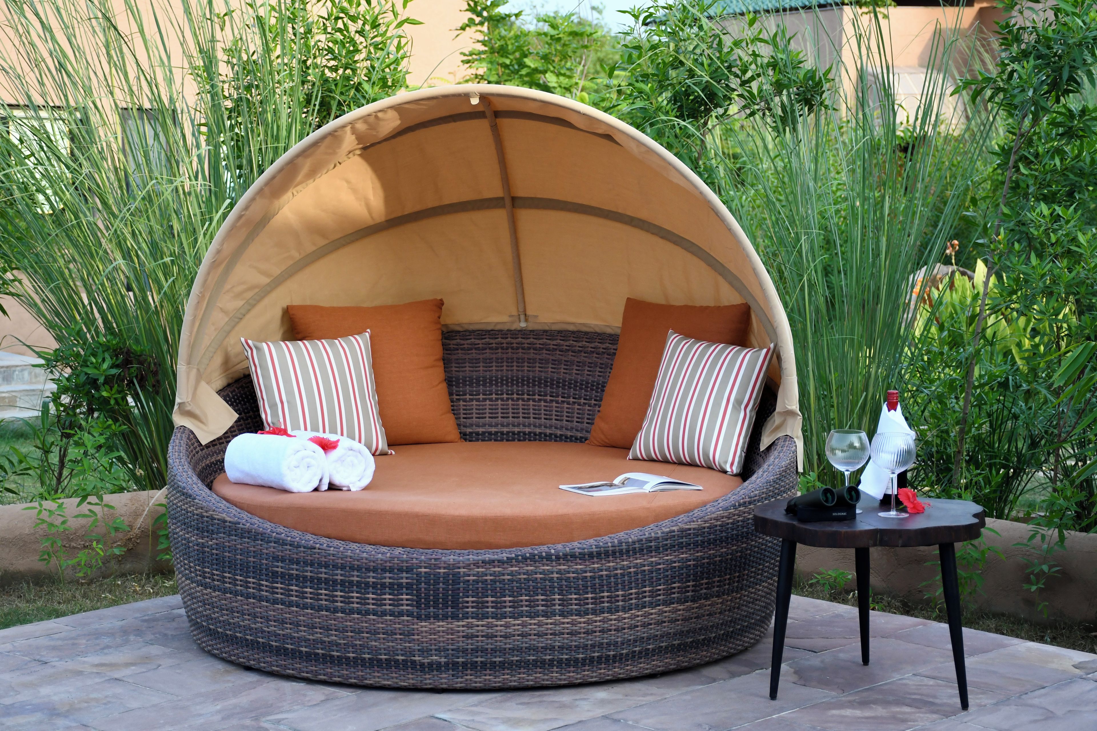 A round, dome-shaped outdoor seating area with a cushioned seat and two pillows.