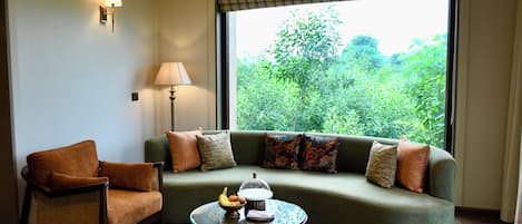 Una habitación con sofá, sillón y una mesita de noche con lámpara.