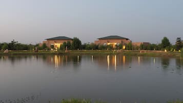 Een gebouw met een plat dak en een reflecterend wateroppervlak ervoor.
