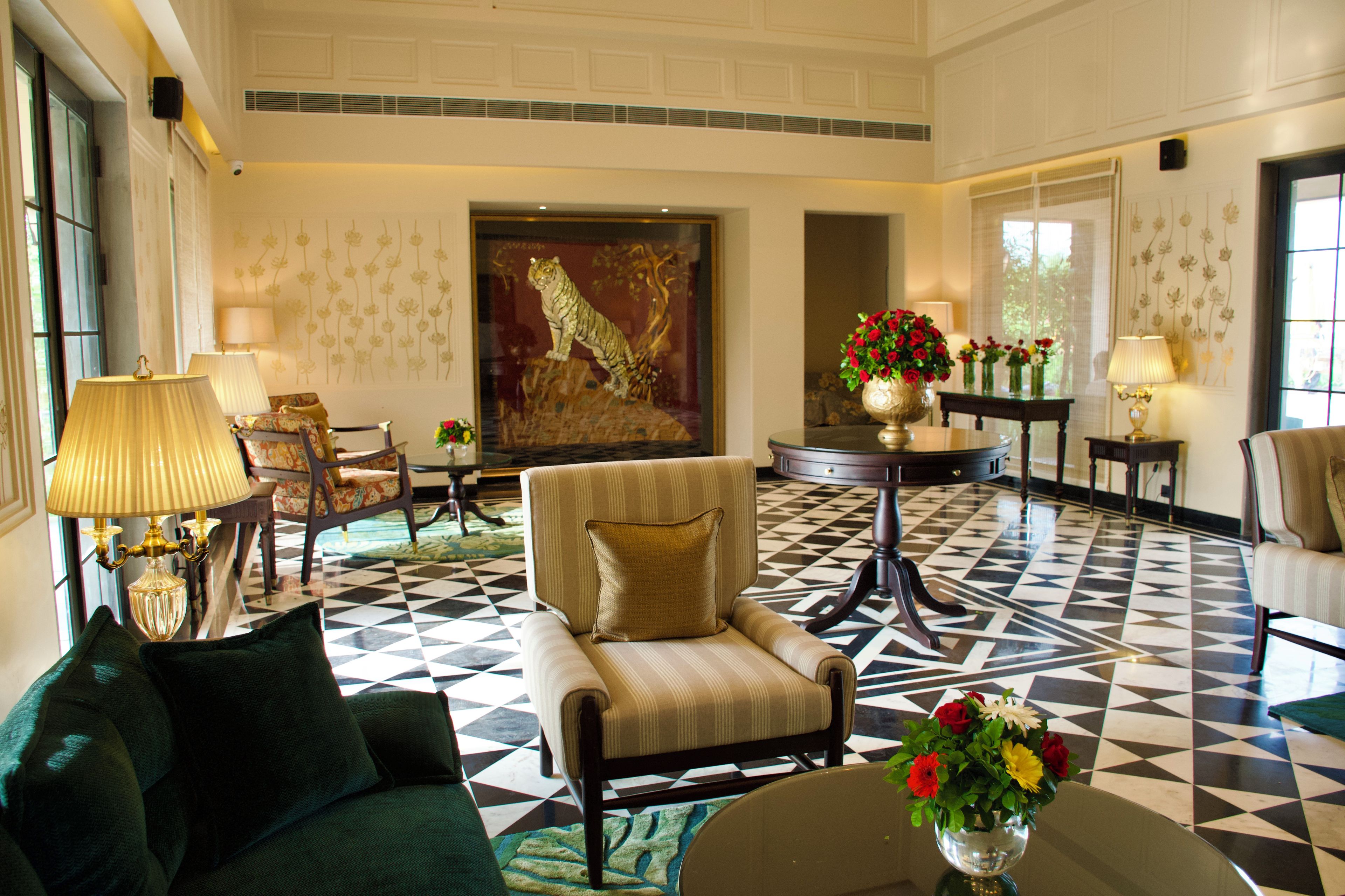 A hotel lobby with a checkered floor, a large tiger mural, and a seating area with a sofa and armchairs.