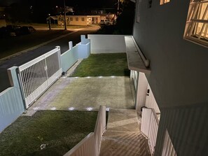 Il s’agit d’une propriété résidentielle dotée d’une cour clôturée, d’un chemin en béton et d’un escalier menant à un balcon.