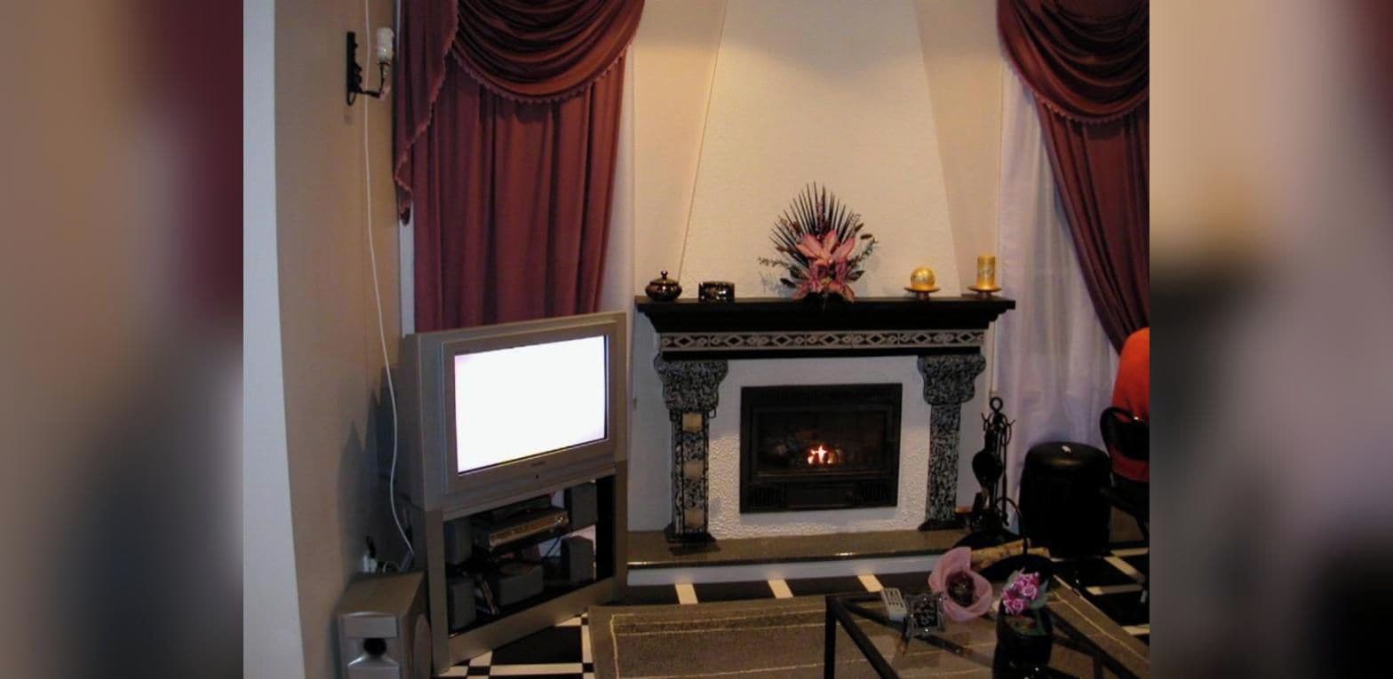 A living room with a fireplace, a television, and a checkered floor.