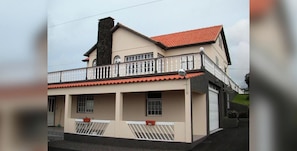 A two-story building with a balcony, a garage, and a chimney.