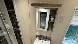 Ein Badezimmer mit Dusche, Waschbecken, Toilette und Spiegel.