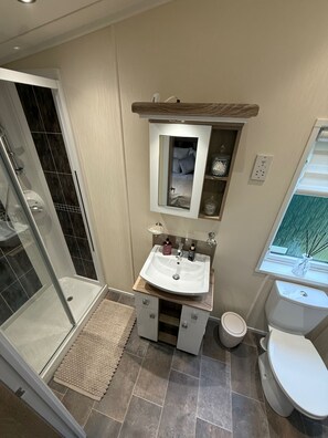 A bathroom with a shower, a sink, a toilet, and a mirror. - Cabin Sleeps 4 With Parking and Balcony (Chester)