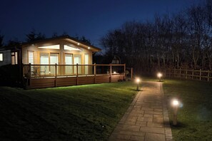 A wooden cabin with a deck, a barbecue area, and a pathway leading to the entrance. - Cabin Sleeps 4 With Parking and Balcony (Chester)