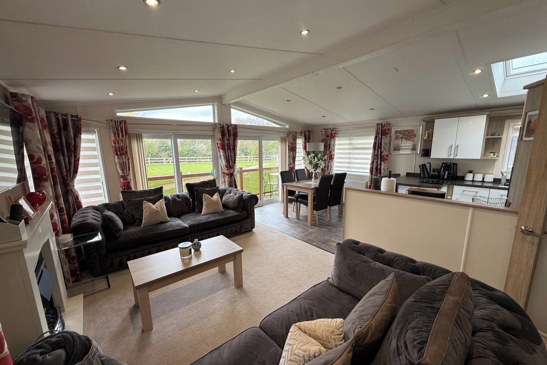 A spacious living area with a sofa set, a dining table, and a kitchen area.