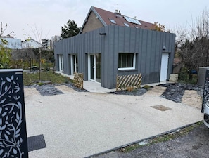 A modern two-story building with a flat roof, large windows, and a paved driveway. - defaultName (Besançon)