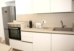 A compact kitchen with a built-in oven, a coffee maker, and a sink.