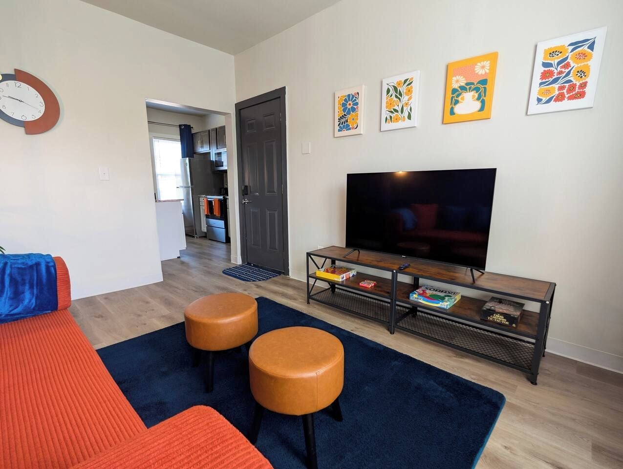 A living room with a sofa, two ottomans, a coffee table, and a flat-screen TV.