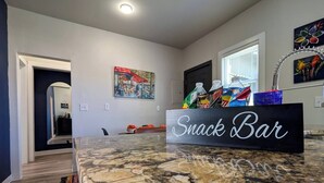 A kitchen area with a 'Snack Bar' sign, a granite countertop, and a window with blinds. - Free Parking | Fast Wi-Fi | DT (Detroit)