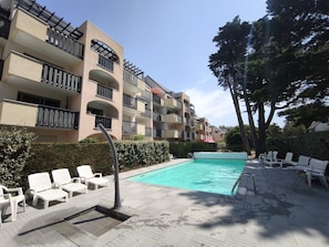 A swimming pool with lounge chairs, a covered seating area, and a multi-story building with balconies. - Le Castel · La Baule · 6 guests · near the beach (La Baule-Escoublac)