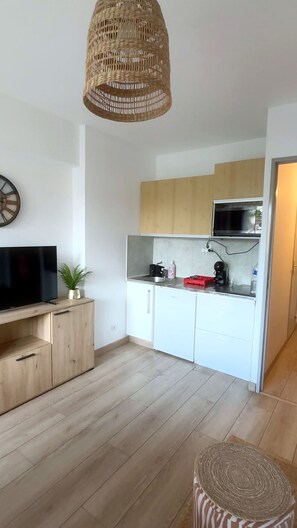 A modern kitchen with wooden cabinets, a built-in microwave, and a hanging light fixture. - Le Castel · La Baule · 6 guests · near the beach (La Baule-Escoublac)
