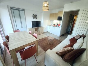 Ein modernes Wohnzimmer mit Essbereich, Küche und Fernseher.