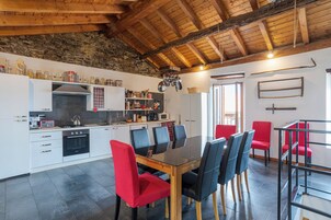 Una cocina moderna con comedor, que presenta una pared de piedra, vigas de madera en el techo y una variedad de electrodomésticos y utensilios de cocina.