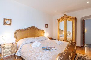 Ein Hotelzimmer mit einem großen Bett, einem Holznachttisch, einem Spiegel und einem Kleiderschrank.