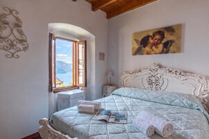 Ein Schlafzimmer mit Bett, Fenster mit Blick, Nachttisch und einem Bild an der Wand.