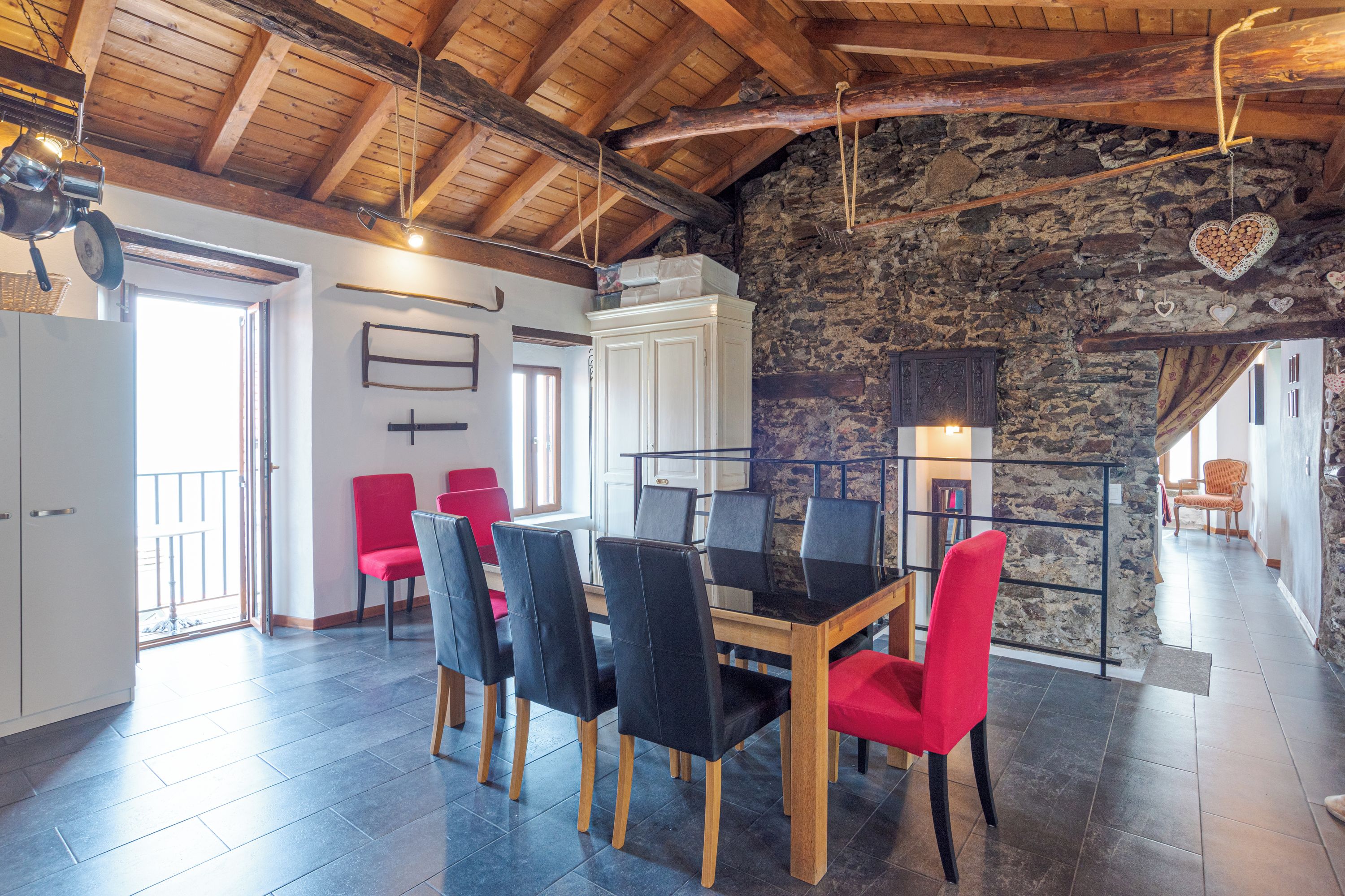 A dining area with a stone wall, a wooden ceiling, and a table with chairs.