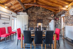 A dining area with a stone wall, wooden beams, and a table set for four.