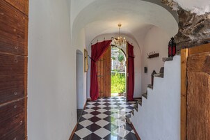 Un pasillo con piso a cuadros, una puerta de madera y una pared de piedra.