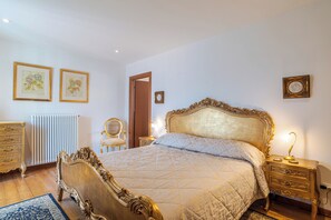 Een klassieke slaapkamer met een groot bed, een versierde kaptafel en een radiator.