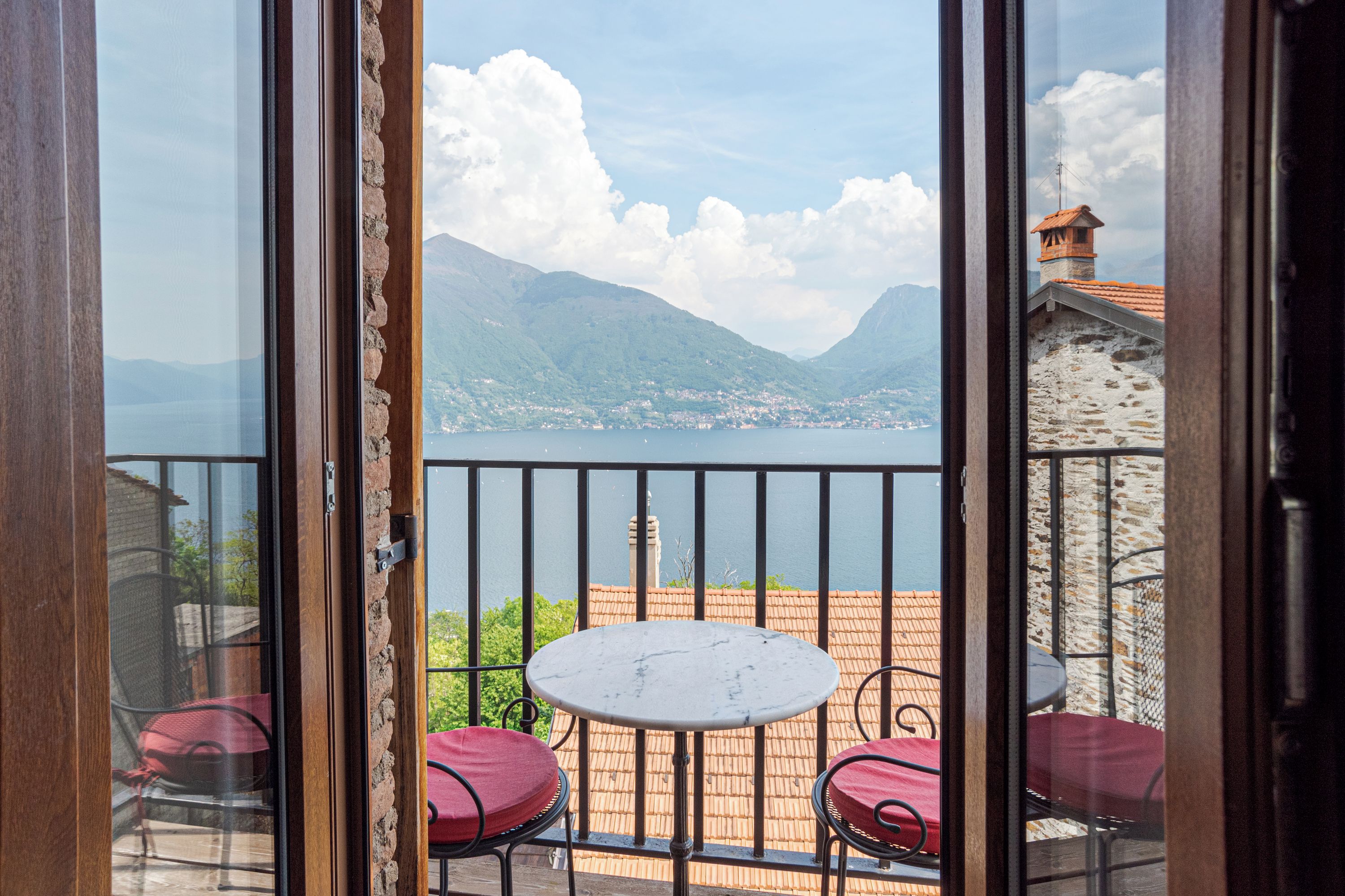 Un balcon avec une table et des chaises, donnant sur un lac et des montagnes.