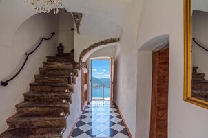 Eine Treppe mit Steinstufen führt zu einem Balkon mit Blick auf Berge und einen See.