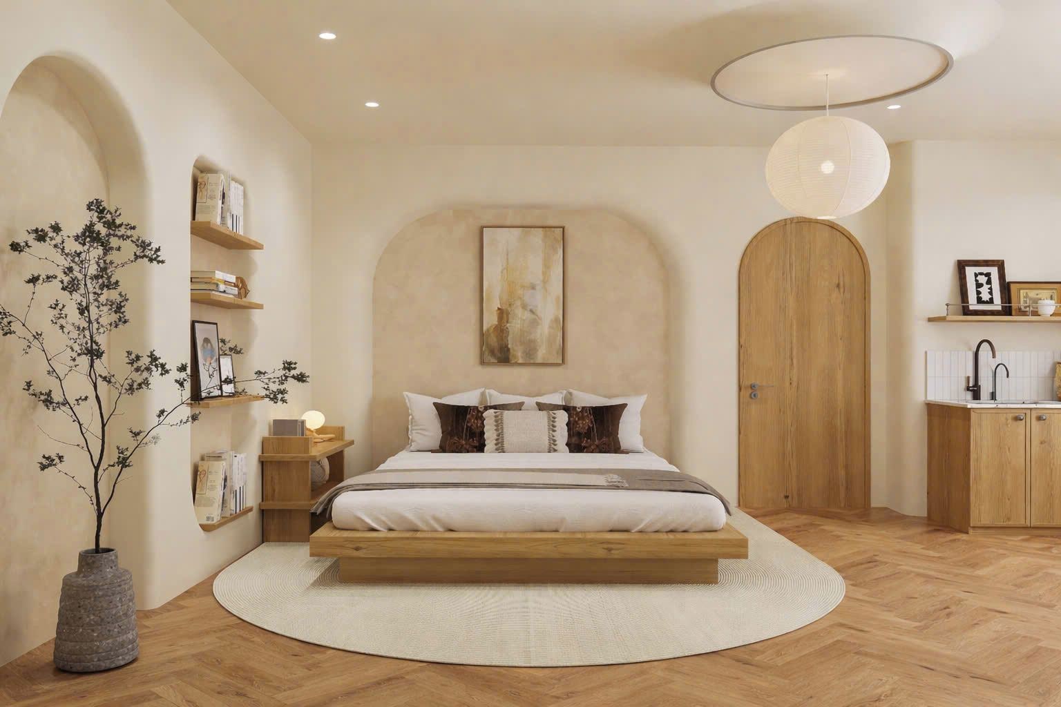A bedroom with a large bed, wooden headboard, a round rug, a bedside table with a lamp, and a wall-mounted shelf with books and a framed picture.