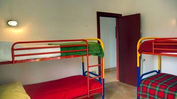 A room with two bunk beds, a door, and a wall-mounted light fixture.