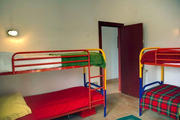 Una habitación con dos literas, una puerta y un aplique en la pared.