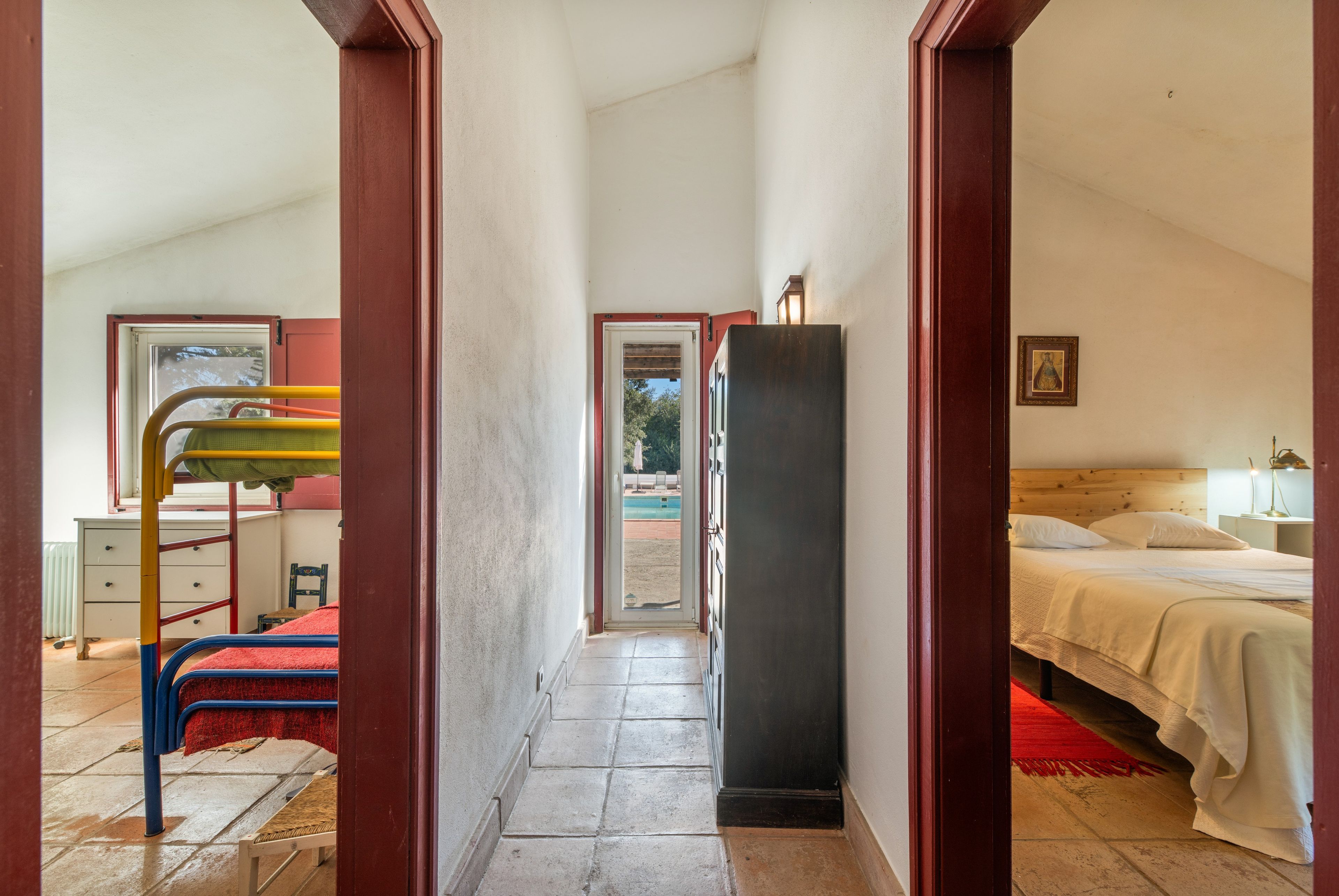 Ein Flur, der zu einem Schlafzimmer mit Bett, Kleiderschrank und Blick ins Freie führt.
