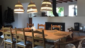 A dining area with a wooden table and chairs, pendant lights, and a view of the outdoors. - Country House 'Monte Do Campaniço' with Mountain View, Private Pool and Wi-Fi (Tanganheira)
