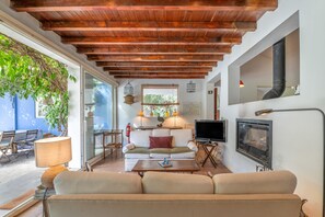 A cozy living room with a wooden ceiling, a sofa, a television, and a fireplace. - Country House 'Monte do Campaniço' between mountains and sea, Private Pool and Wi-Fi (Tanganheira)