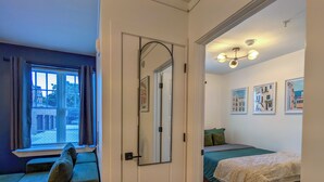 Une pièce comprenant un lit, un coin salon et une porte donnant sur une autre pièce.