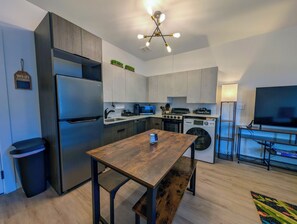 Een moderne keuken met roestvrijstalen apparatuur, een eettafel en een televisie in de woonkamer.