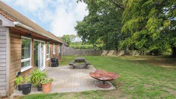 A backyard with a wooden deck, a barbecue grill, and a picnic table.