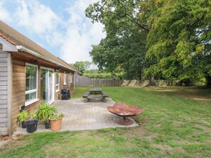Ein Garten mit einer Holzterrasse, einem Grill und einem Picknicktisch.