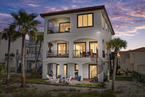 Edifício residencial com várias andares, varandas, área de estar ao ar livre e palmeiras.