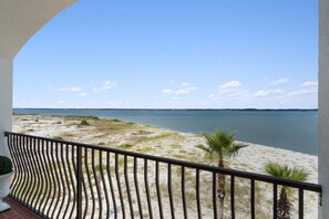 A balcony with a view of a calm body of water and distant shoreline. - Luxury Soundfront Home in Gated Community with Water Views, Pool & Fire Pit (Navarre Beach)