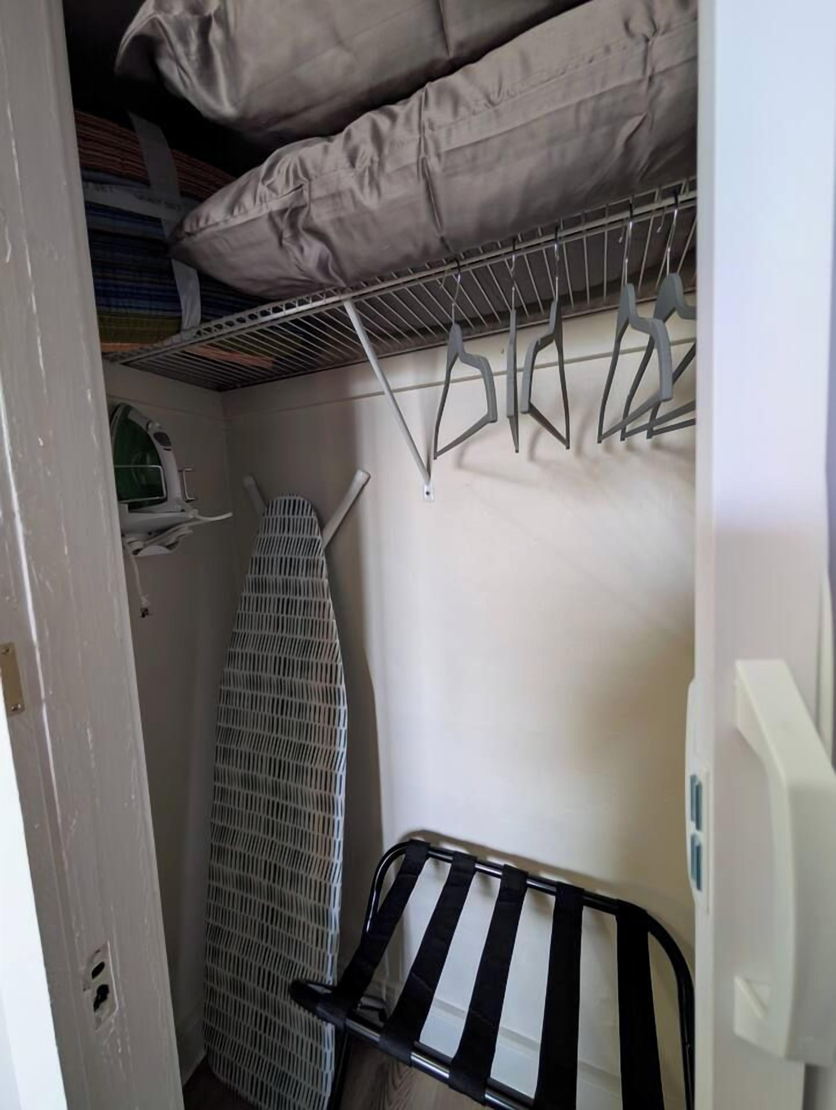 A compact room with a bed, a drying rack, and a radiator.