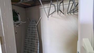 A compact room with a bed, a drying rack, and a radiator.