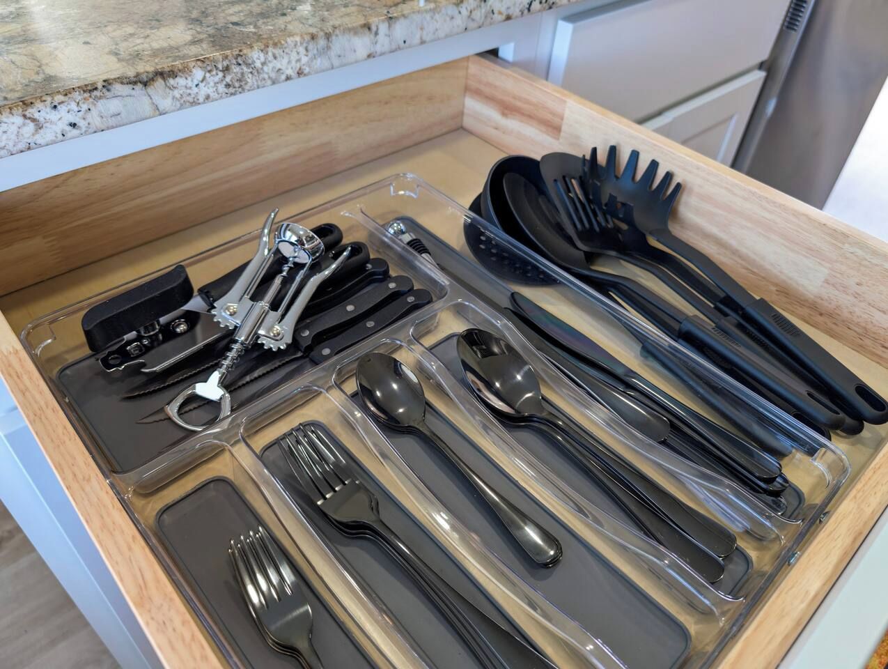A drawer with various kitchen utensils neatly organized in compartments.