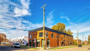 Un edificio de varios pisos con fachada de ladrillo, una tienda a la vista y vista a la calle.