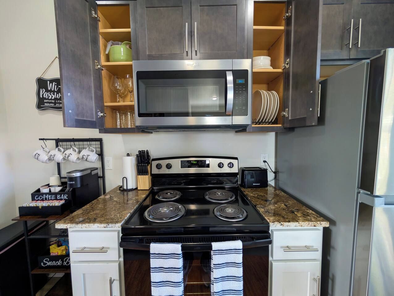 A kitchen with a stainless steel microwave, a stove, and a refrigerator.