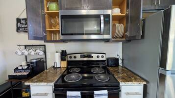A kitchen with a stainless steel microwave, a stove, and a refrigerator.