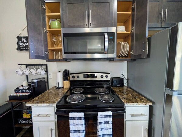 A kitchen with a stainless steel microwave, a stove, and a refrigerator.