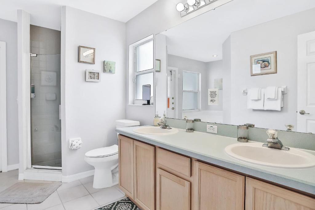 A modern bathroom with two sinks, a toilet, and a shower.